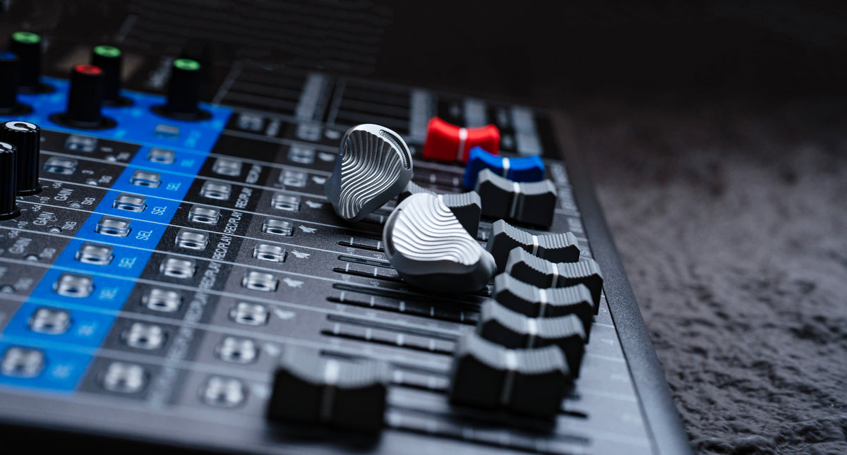 ZiiGaat x Jay's Audio Seraphim earphones resting on the faders of a mixing desk