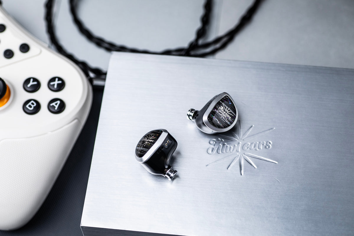 Kiwi Ears Aether on a brushed metal plate next to a white game controller and black cable