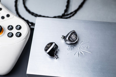 Kiwi Ears Aether on a brushed metal plate next to a white game controller and black cable